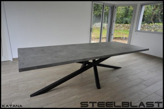 Table moderne avec un plateau en béton et des pieds en métal noir, design minimaliste.